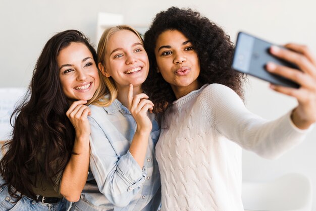 Mujeres jóvenes en la oficina tomando selfies