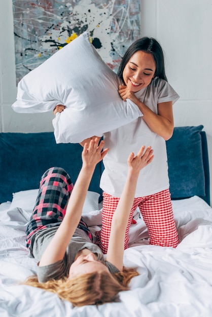 Foto gratuita mujeres jóvenes peleando por almohadas.