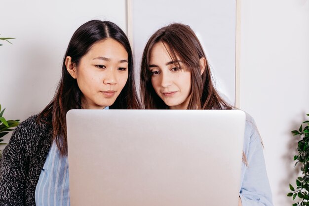 Mujeres jóvenes de pie con la computadora portátil