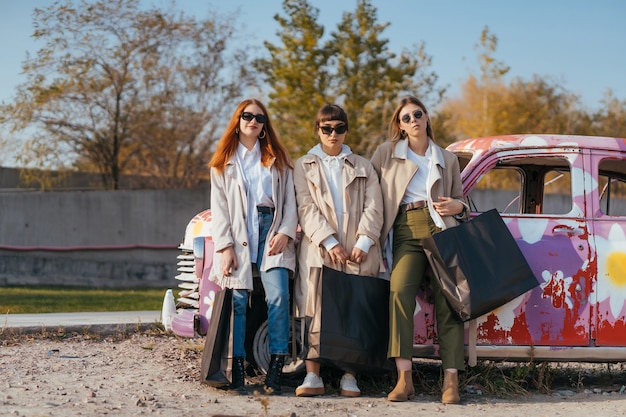 Mujeres jóvenes posando cerca de un viejo coche decorado
