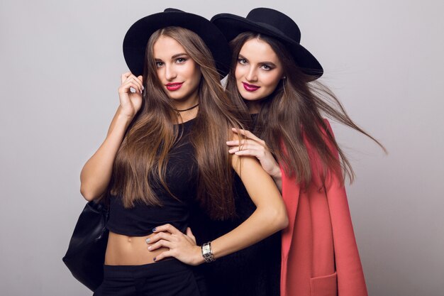 Mujeres jóvenes posando y vistiendo elegantes sombreros negros