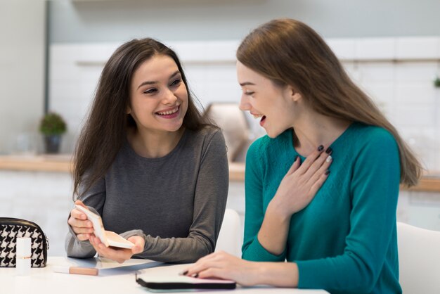 Mujeres jóvenes positivas felices con accesorios de maquillaje