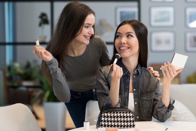 Foto gratuita mujeres jóvenes positivas felices con accesorios de maquillaje