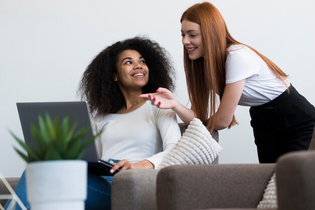 Mujeres jóvenes positivas que trabajan juntas en una computadora portátil