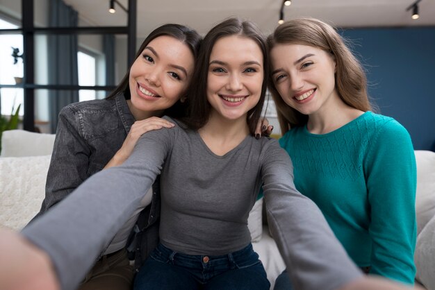 Mujeres jóvenes positivas tomando una foto juntas
