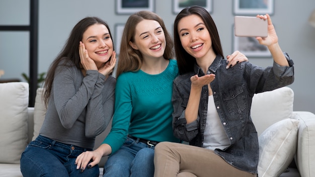 Mujeres jóvenes positivas tomando una selfie juntos