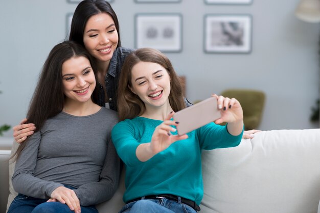 Mujeres jóvenes positivas tomando una selfie juntos