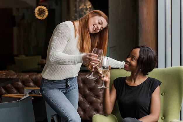 Mujeres jóvenes positivas tomando vino juntos