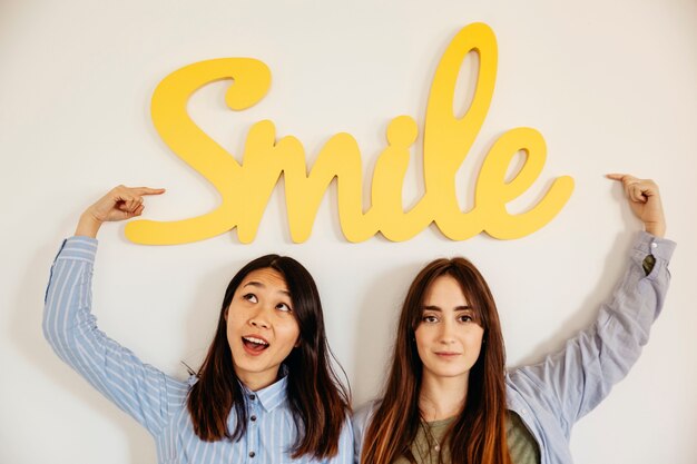 Mujeres jóvenes que apuntan a la escritura de la sonrisa