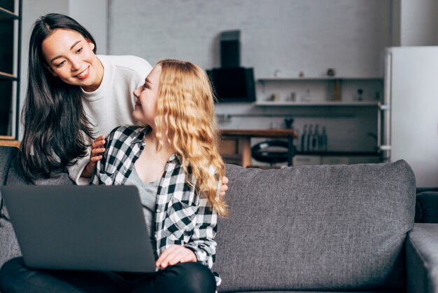 Mujeres jovenes que hablan y que practican surf en la computadora portátil