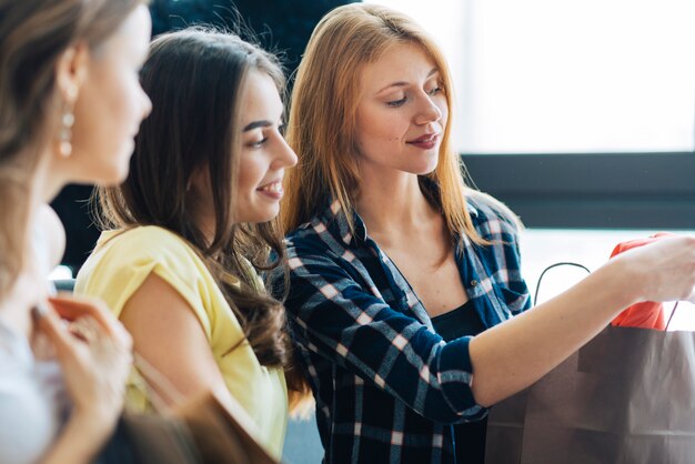 Mujeres jóvenes que miran compras juntas