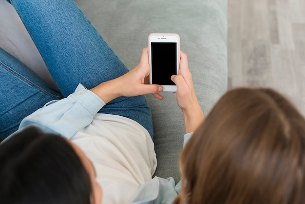 Foto gratuita mujeres jovenes que miran smartphone en blanco