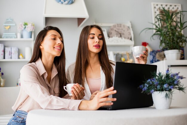 Mujeres jóvenes que trabajan en la computadora portátil en casa