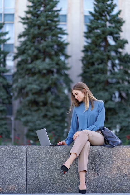 Mujeres jóvenes que trabajan en la computadora portátil en la plaza de la ciudad