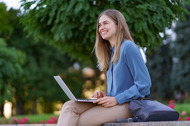 Mujeres jóvenes que trabajan en la computadora portátil en la plaza de la ciudad