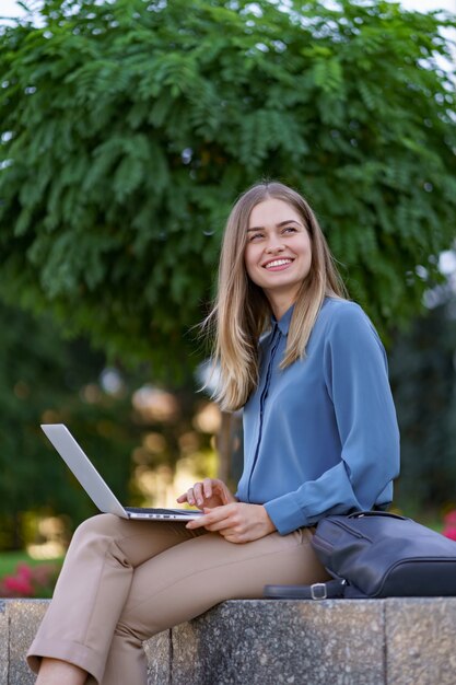 Mujeres jóvenes que trabajan en la computadora portátil en la plaza de la ciudad