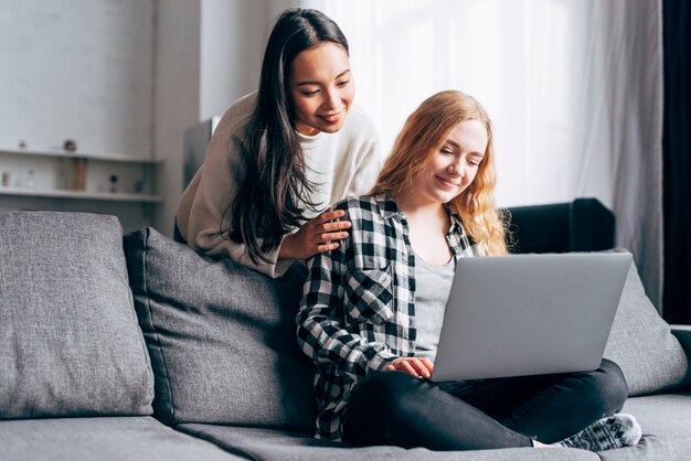 Mujeres jovenes que usan el ordenador portátil en casa