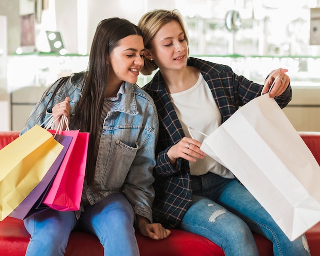 Foto gratuita mujeres jóvenes revisando bolsas de compras