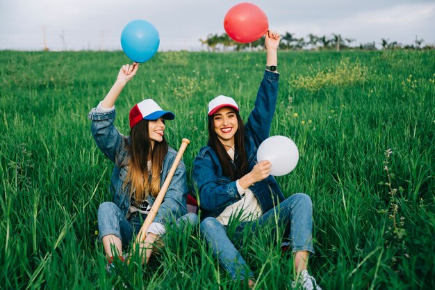 Mujeres jóvenes riendo en el campo con globos