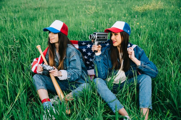 Las mujeres jóvenes en ropa de jeans sentado con cámaras retro