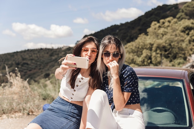 Mujeres jóvenes sentados en coche posando para autorretrato