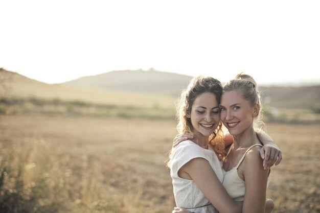 Mujeres jóvenes sonriendo y abrazándose en el campo