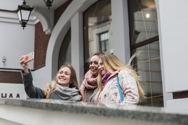 Foto gratuita mujeres jóvenes tomando selfie en edificio