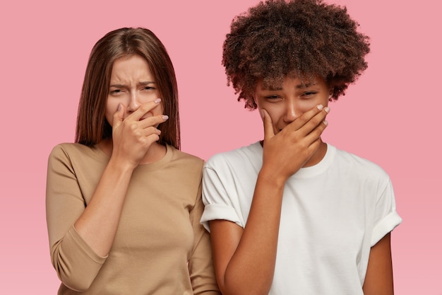 Las mujeres jóvenes tristes tienen dolor, lloran y miran con expresión desesperada, se sienten desesperadas, miradas miserables, modelan contra la pared rosa, tienen un evento trágico o una pérdida, no pueden detener los sentimientos negativos.