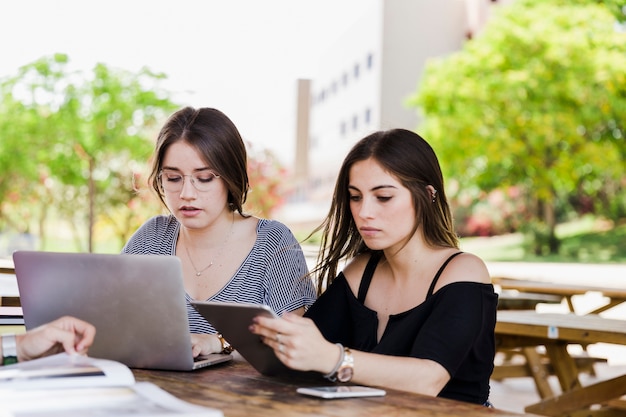 Mujeres jóvenes usando gadgets en la mesa