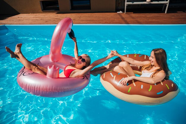 Mujeres jugando en la piscina con anillos de natación.