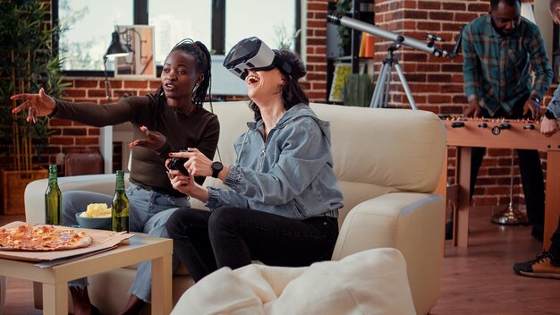 Mujeres jugando videojuegos con gafas vr en la consola, usando auriculares 3d de realidad virtual para jugar a la competencia de juegos. Divirtiéndose con la simulación de juegos en la reunión de la fiesta, bebiendo cerveza.