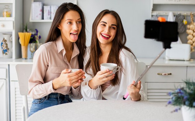 Mujeres juguetonas en casa tomando selfies