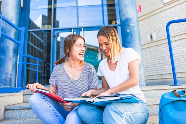 Mujeres leyendo libros de texto y riendo