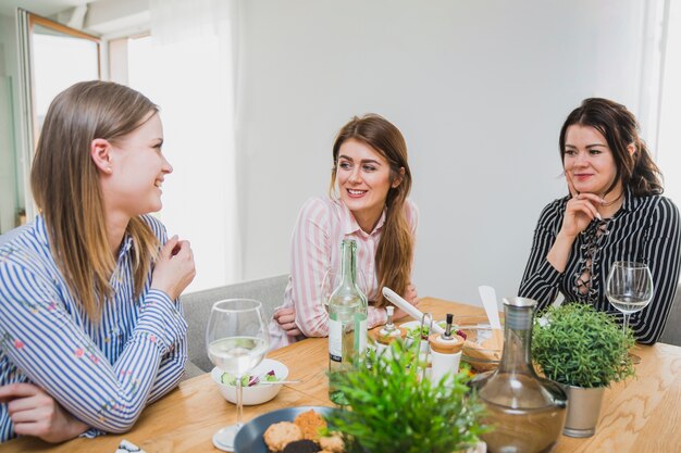 Mujeres lindas en mesa charlando y sonriendo