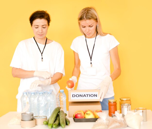 Mujeres llenando cajas de donaciones con comida