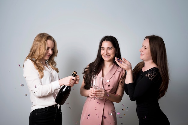 Foto gratuita mujeres de lujo que abren la botella de champán con fiesta