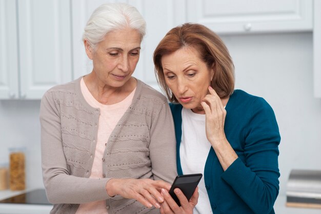 Mujeres maduras revisando un teléfono juntos