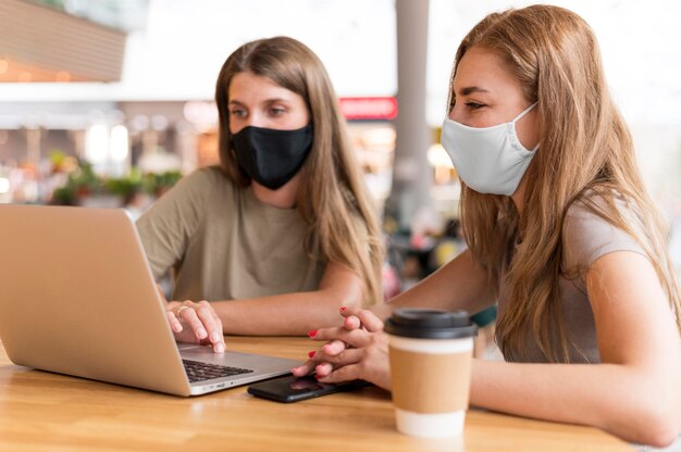 Mujeres con máscara trabajando en laptop