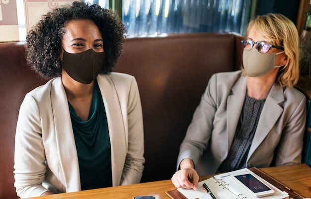 Mujeres en mascarilla en el café durante el almuerzo