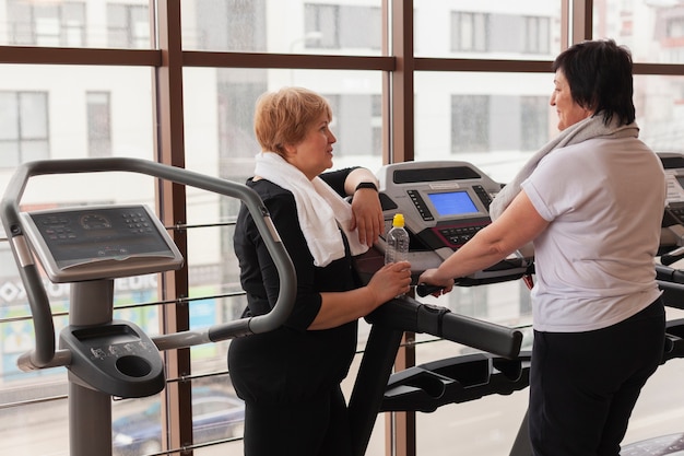 Foto gratuita mujeres mayores de alto ángulo que trabajan en la cinta de correr