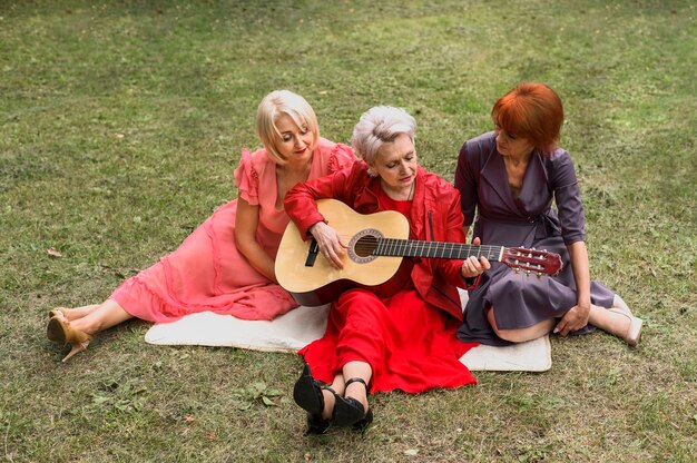 Mujeres mayores del ángulo alto que juegan música