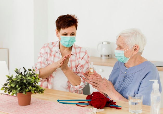 Mujeres mayores desinfectando sus manos mientras están en casa