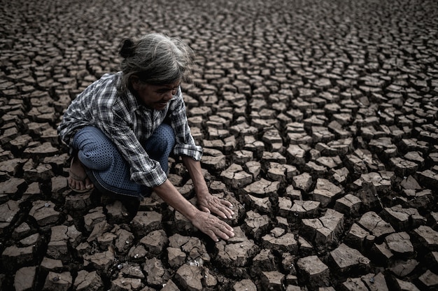 Foto gratuita las mujeres mayores están sentadas mirando sus manos, tocando el suelo en clima seco, el calentamiento global