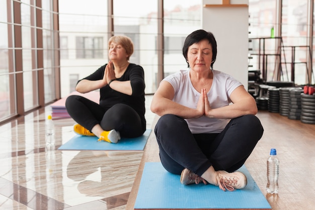 Mujeres mayores en el gimnasio haciendo yoga