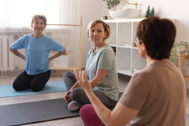 Mujeres mayores haciendo ejercicios juntos en casa y hablando