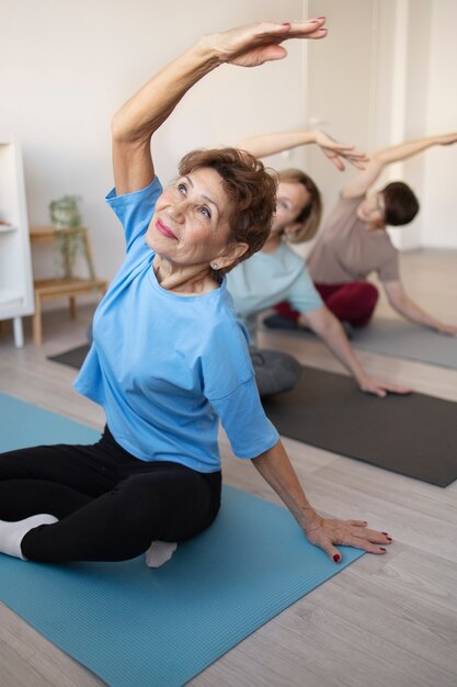 Mujeres mayores haciendo yoga y fitness juntas en casa
