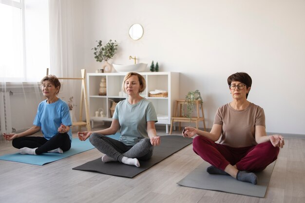 Mujeres mayores haciendo yoga juntas en casa