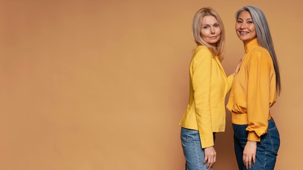 Mujeres mayores posando sobre un fondo amarillo