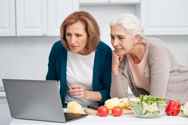 Mujeres mayores que buscan recetas de cocina