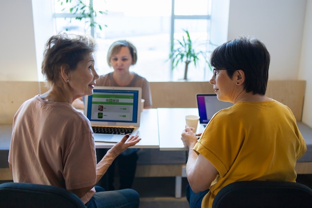 Mujeres mayores que pasan tiempo juntas en un café hablando y trabajando